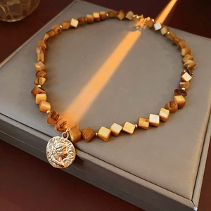 Macro shot of brown square beads and golden coin pendant on a retro style necklace