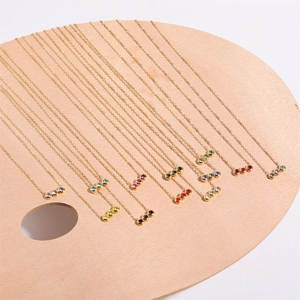 Collana con tre pietre natali tonde in acciaio inossidabile dorato su tavolozza di legno
