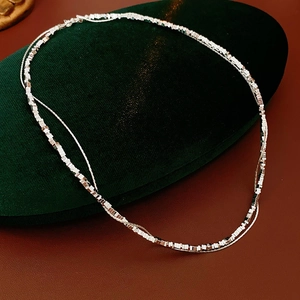 Close-up of double-layer silver chain necklace on green velvet jewelry box
