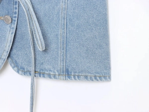 Détail du tissu denim bleu clair avec coutures de précision et bouton en métal de qualité