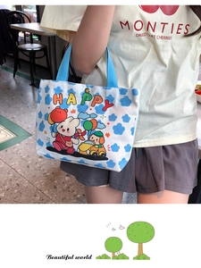 Detail of compact canvas tote featuring happy cartoon prints and blue ribbon handles