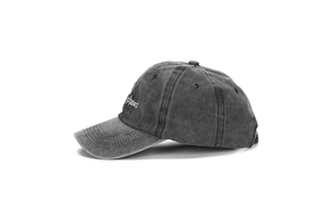 Dettaglio del ricamo bianco gotico sul cappellino in tela di cotone grigio lavato