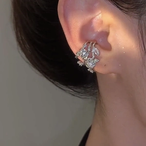 Detail of silver triple-layered flower ear cuff with zircons worn on model's ear