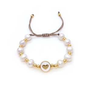 Close-up of handmade baroque pearl bracelet featuring a gold heart charm and brown cord