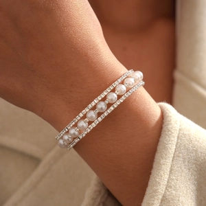 Close-up of three-row silver layered bracelet with faux pearls and sparkling rhinestones
