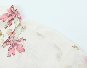 Detail der floralen Leinenbluse mit Kragenpartie, beiger Stoffstruktur und rosa Blumendruck