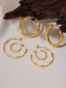 Detailed shot of gold PVD plated stainless steel hoop earrings on natural wood decor