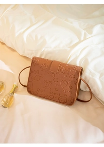 Detail of cute cartoon embossed patterns on brown leather shoulder bag surface
