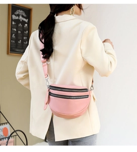 Pink crossbody bag with double zippers and wide adjustable strap shown on model's shoulder