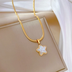 Detail of gold star pendant with white mother of pearl inlay on snake chain necklace