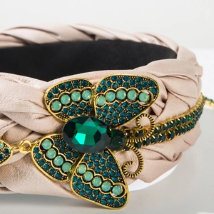Detail eines rosa geflochtenen Lederstirnbands mit Vintage-Schmetterling und grünen Steinen