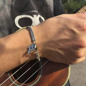 Men's double-layered silver cross bracelet with braided metal chain in lifestyle shot