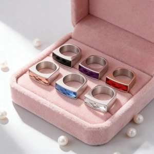 Stack of titanium steel rings with colored rectangular glass gems in a pink velvet box