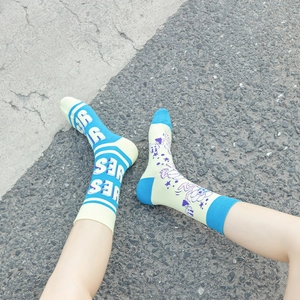 Close-up of asymmetrical blue and yellow cotton socks with YES lettering on asphalt background