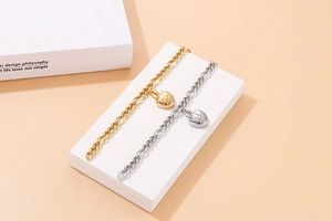 Close-up of gold and silver heart pendants on Figaro chains over geometric blocks