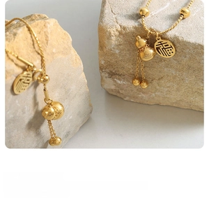 Detail of gold gourd necklace with Fu character charm on natural stones