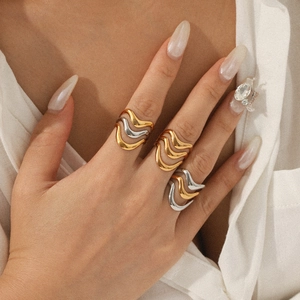 Two-tone wavy stackable rings in gold and silver finish on model's hand