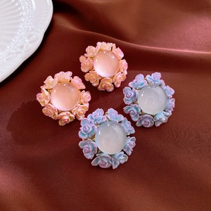 Close-up of elegant floral earrings with pink and light blue resin petals on silk fabric