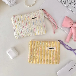 Detail of cream and yellow fabric makeup pouches with woven zippers and brand labels