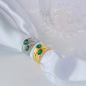 Detailed close-up of wide gold and silver rings set with oval emerald green cubic zirconia