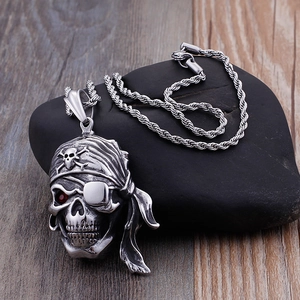 Pendentif tête de mort pirate rétro détaillé avec œil en rubis posé sur pierre sombre