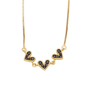 Detail of gold box chain necklace featuring triple heart charms with black stone inlay