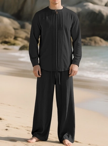 Detail eines schwarzen Baumwoll-Leinen-Sets mit Plisseehemd vor Strandkulisse