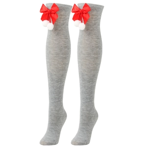 Detail of gray knitted over-knee socks with red bows and white plush pom-poms for Christmas