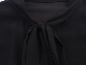Dettaglio dell'elegante abito nero con patchwork in pizzo e scollo con fiocco