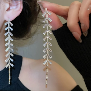 Vue détaillée de longues boucles d'oreilles feuilles dorées avec oxydes de zirconium