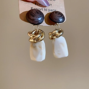 Détail macro du clou d'oreille en bois avec anneau doré et pendentif en résine marbrée