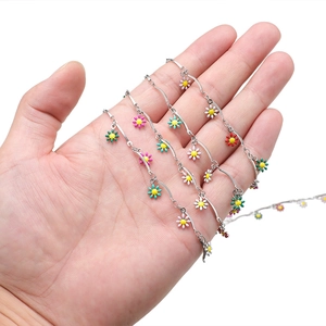 Detail of 15mm stainless steel chain with colorful daisy charms held in hand