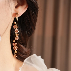 Close-up of model wearing gold tassel earrings with champagne roses and crystals