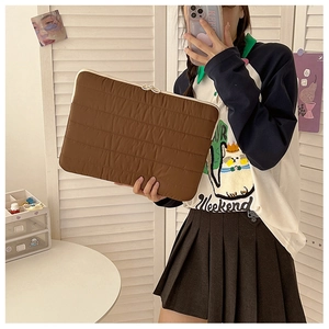 Quilted caramel laptop sleeve with cream zipper shown in a modern lifestyle setting