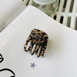 Gros plan d'une pince à cheveux en acétate léopard posée sur les pages d'un livre blanc