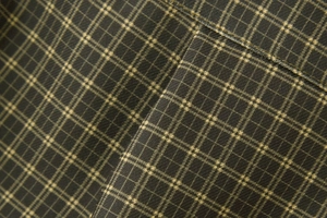 Macro detail of dark green plaid fabric texture with precise stitching for shirts