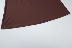 Detailed close-up of brown knit dress hem with professional stitching and soft texture