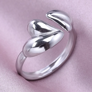 Macro shot of polished silver dual heart open ring on smooth lavender silk fabric