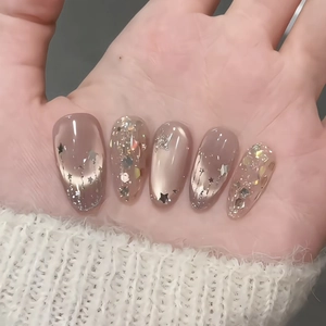 Handmade press-on nails featuring nude gradient with silver stars and glitter sequins