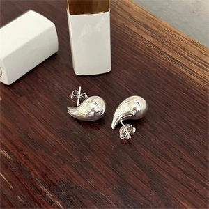 Minimalist 925 sterling silver water drop stud earrings on a vintage wooden background