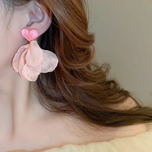 Détail de la boucle d'oreille cœur rose en résine avec des pétales en tulle sur mannequin