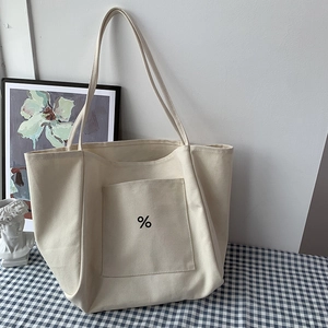Close-up of minimalist cream canvas tote bag with black percent symbol in lifestyle setting