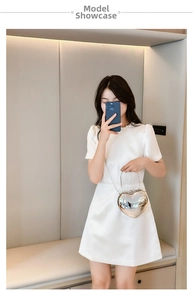 Silver mirror heart-shaped crossbody bag with metal ring handle and chain strap on model