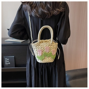 Detail der handgefertigten Stroh-Eimertasche mit Tulpenstickerei und Perlenkette