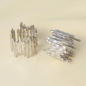 Detail of two silver liquid metal rings with irregular melted lava texture and open bands