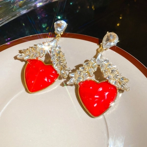 Vue macro des boucles d'oreilles cœur rouge avec cristaux en feuille sur céramique