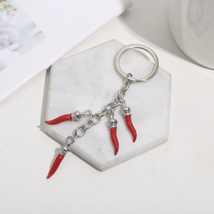 Detail of red chili pepper pendants on a silver keychain over marble coaster