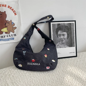 Detail of embroidered grey denim hobo bag featuring colorful icons like apples and cars