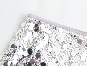 Detail of silver sequin mini dress showing large round sequins and fine edge stitching
