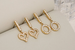 Detailed macro of gold heart and circle earrings encrusted with white rhinestones